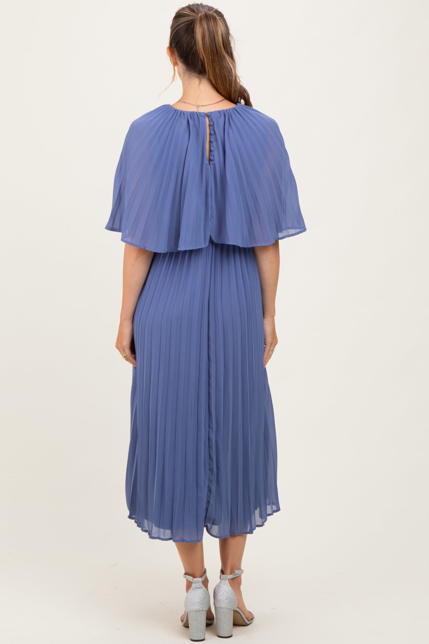 woman wearing a pleated mauve maternity dress with a cape overlay and a keyhole back detail