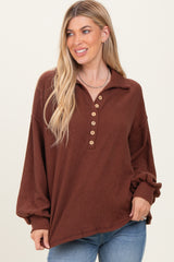 woman wearing a rust brown button-up collared oversized ribbed sweater with long sleeves and a relaxed fit
