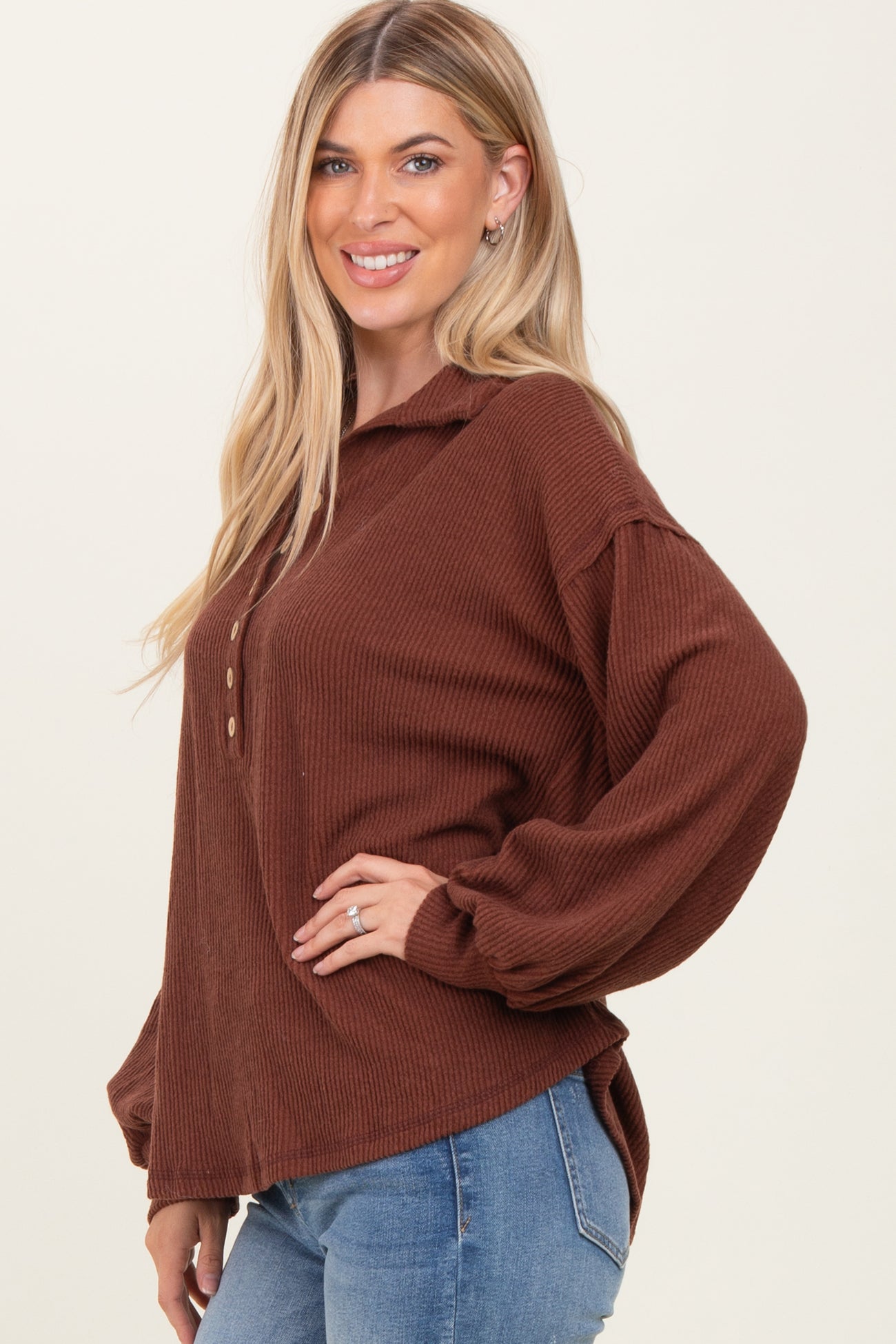 woman wearing a brown ribbed long sleeve top with a collar and button details, paired with blue jeans