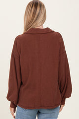woman wearing a rust-colored oversized ribbed sweater with a collar and balloon sleeves, viewed from the back