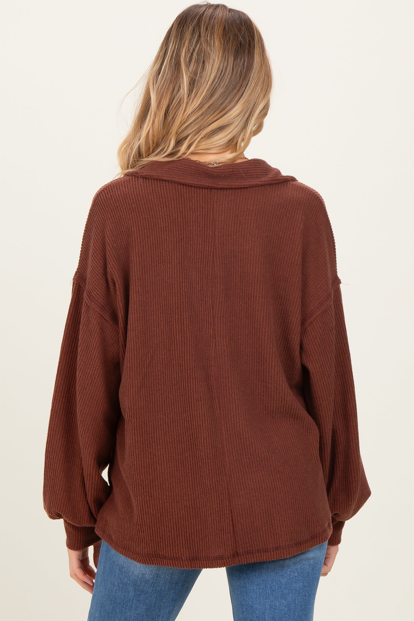 woman wearing a brown ribbed oversized maternity top, showcasing the back view with long sleeves and a relaxed fit
