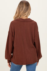 woman wearing a brown ribbed oversized maternity top, showcasing the back view with long sleeves and a relaxed fit