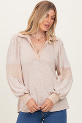 woman wearing a beige collared pullover top with balloon sleeves and a v-neckline, styled casually with denim jeans