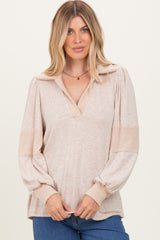 woman wearing a beige long sleeve pullover top with a v-neck and ribbed sleeves, styled casually with jeans