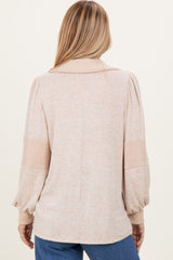 woman wearing a beige oversized sweater with balloon sleeves and ribbed detailing, viewed from the back