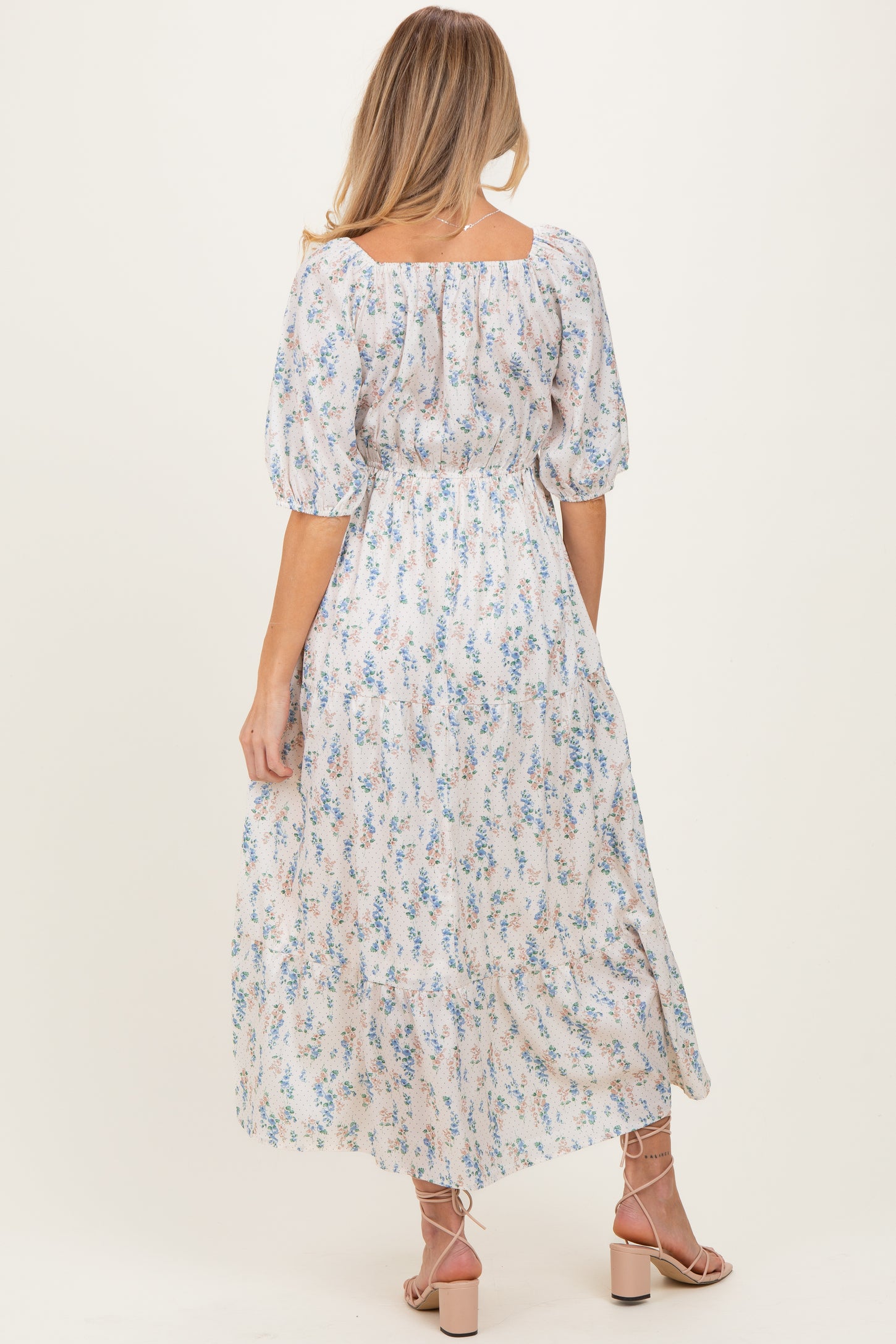 woman wearing a floral maternity dress with puff sleeves and a tiered skirt viewed from the back