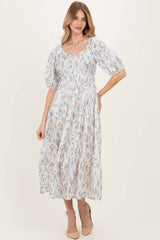 woman wearing a floral midi dress with puff sleeves and a square neckline, standing in a light background