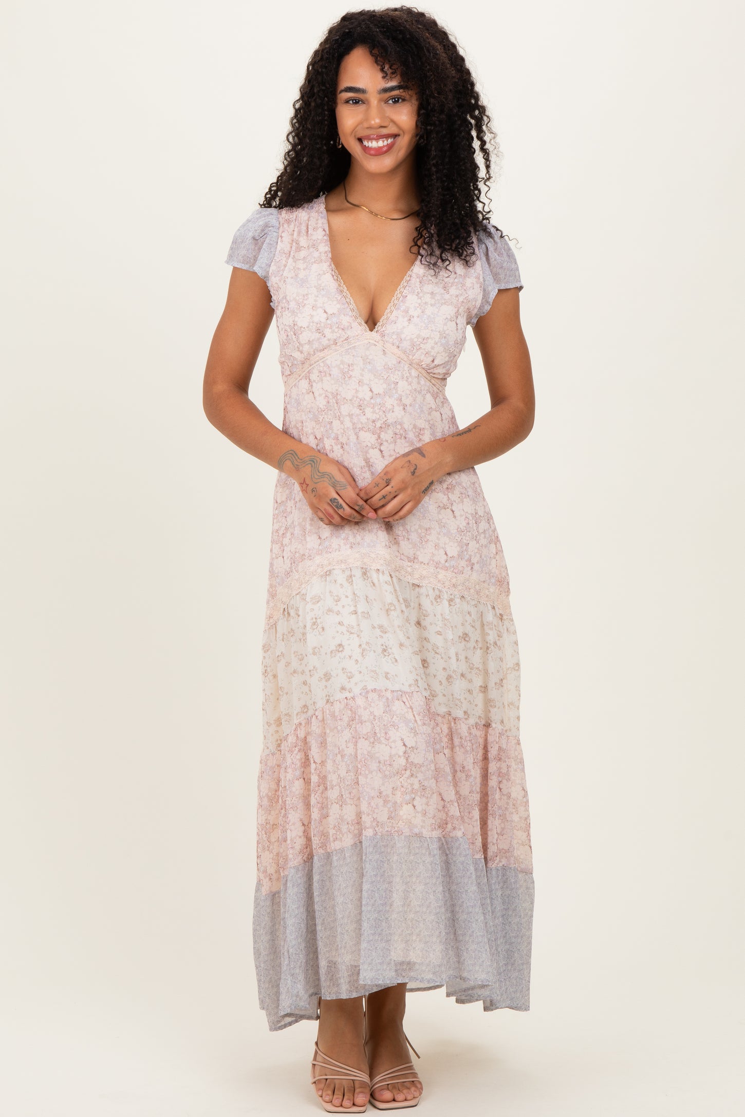 woman wearing a pink and gray floral maxi dress with short puff sleeves and a deep v-neckline