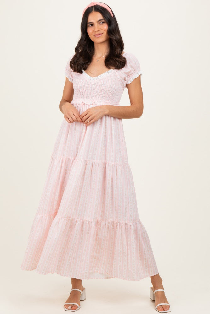 woman wearing a light pink tiered maxi dress with short puff sleeves and a smocked bodice