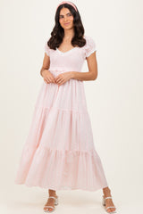 woman wearing a light pink tiered maxi dress with short puff sleeves and a smocked bodice