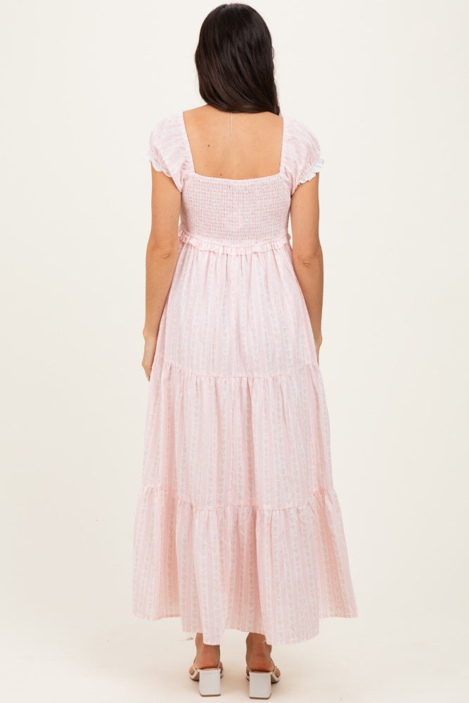 woman wearing a pink striped maxi dress with smocked bodice and tiered skirt, viewed from the back