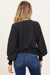 woman wearing a black maternity top with white polka dots and balloon sleeves, view from the back