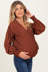 woman wearing a brown polka dot maternity top with a deep v-neckline and puff sleeves, showing her baby bump