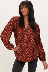 woman wearing a rust-colored blouse with white polka dots and long puff sleeves, styled with a relaxed fit