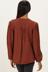 woman wearing a brown polka dot blouse with puff sleeves and a gathered back detail
