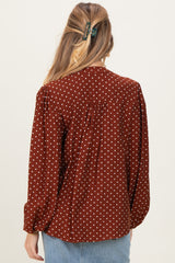 woman wearing a brown polka dot maternity blouse with a relaxed fit and back pleat detail