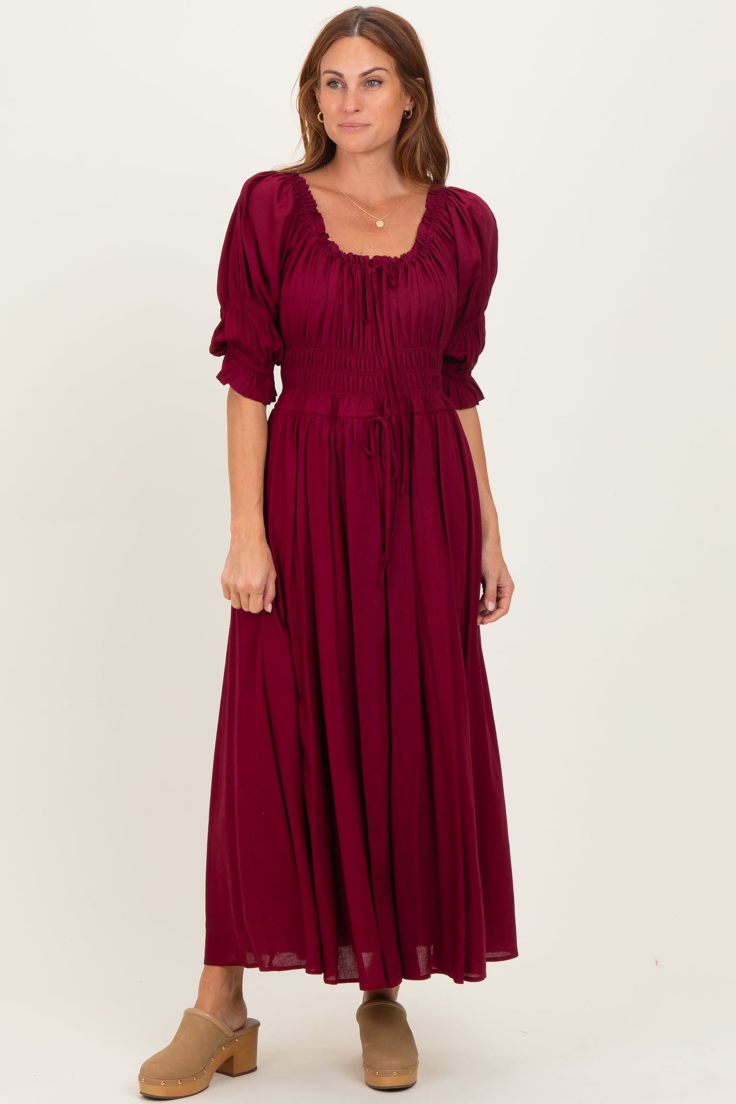 woman wearing a burgundy puff sleeve maxi dress with a smocked bodice and drawstring detail