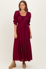 woman wearing a burgundy puff sleeve maxi dress with a smocked bodice and drawstring detail