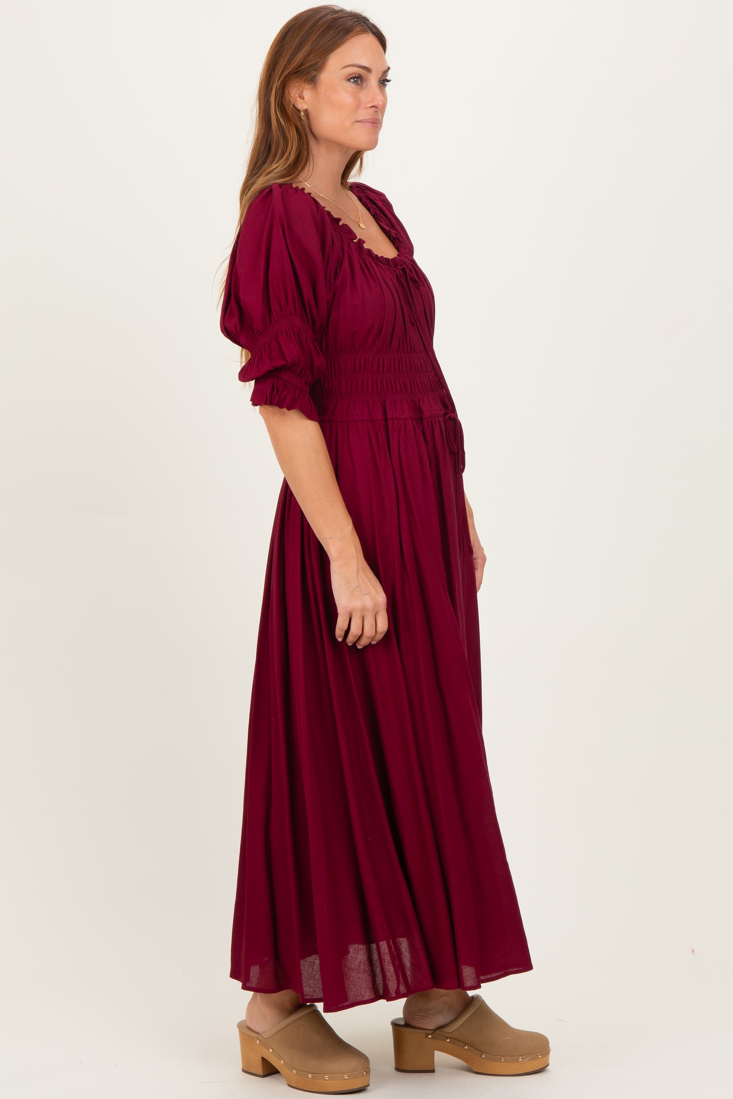 woman wearing a burgundy maxi dress with puff sleeves and a smocked bodice