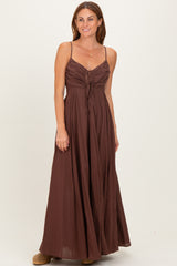 woman wearing a brown spaghetti strap maxi dress with ruching and a tie detail at the bodice