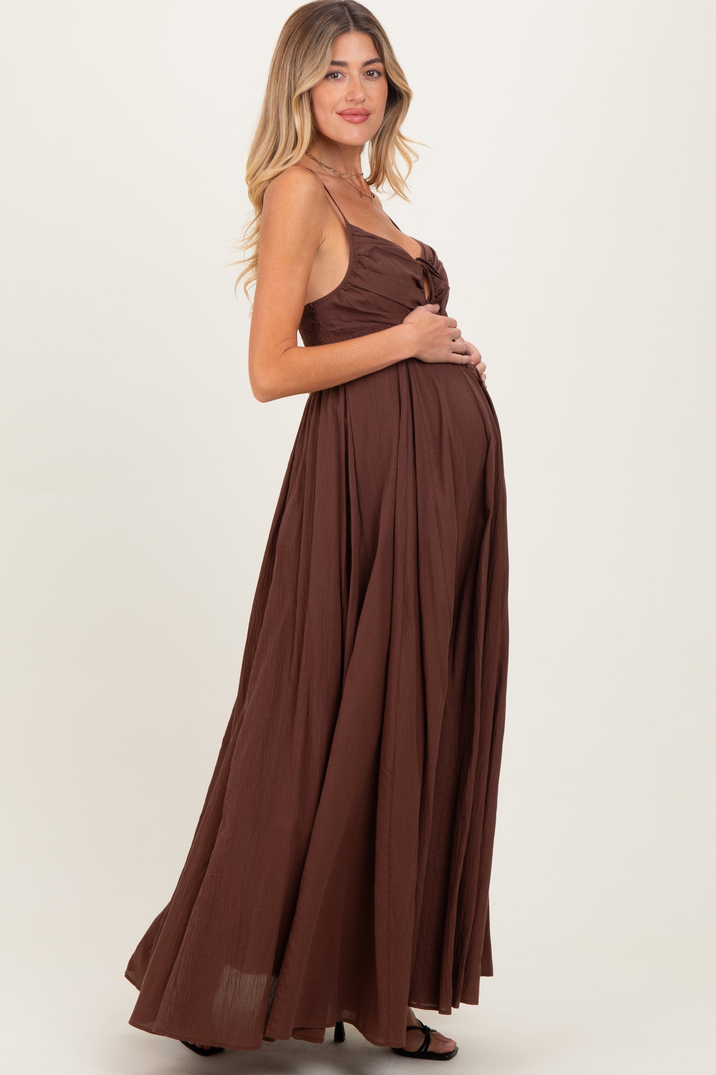 woman wearing a brown maternity maxi dress, showing off her baby bump