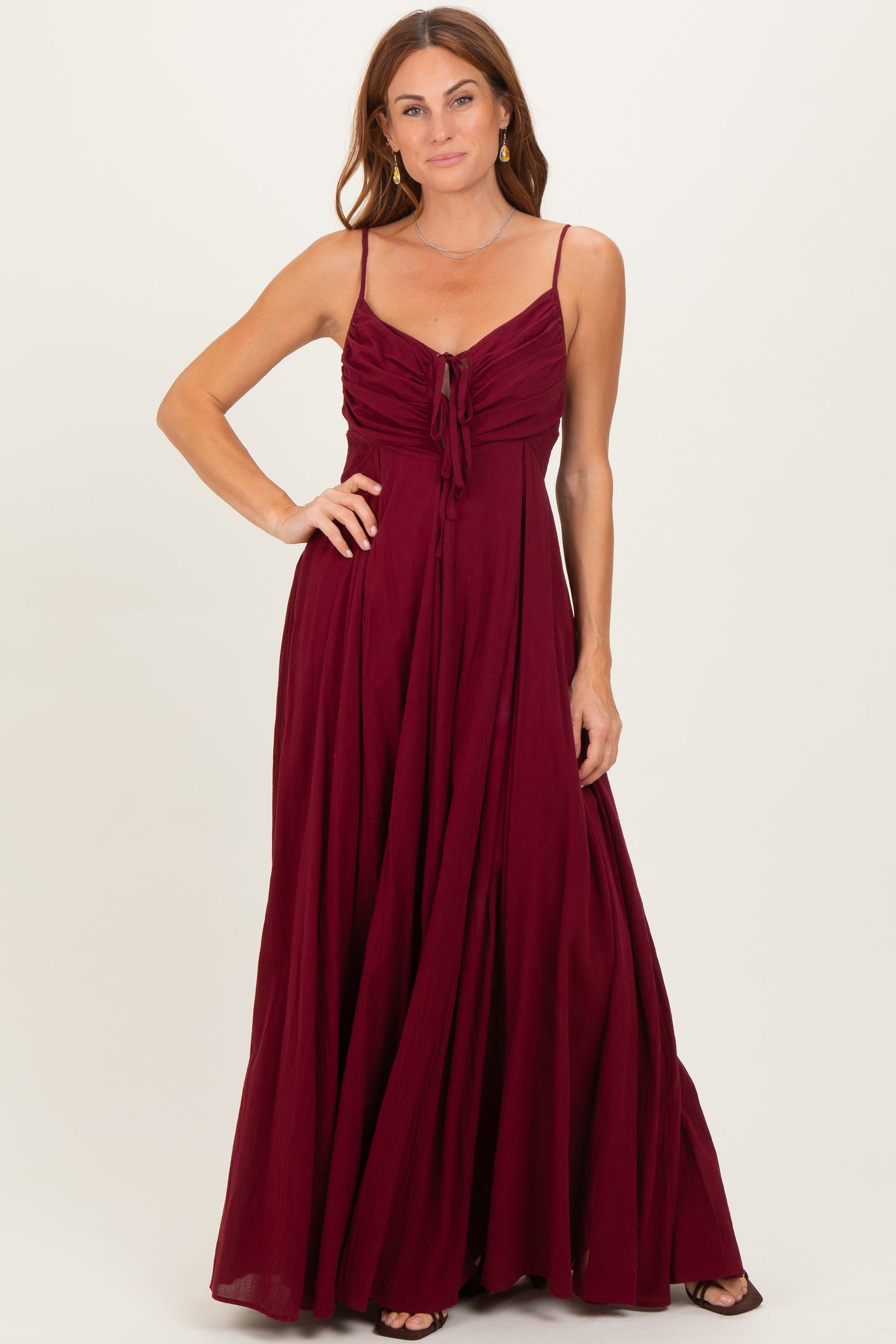 woman wearing a burgundy maxi dress with adjustable straps and a tie front detail