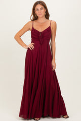 woman wearing a burgundy maxi dress with adjustable straps and a tie front detail