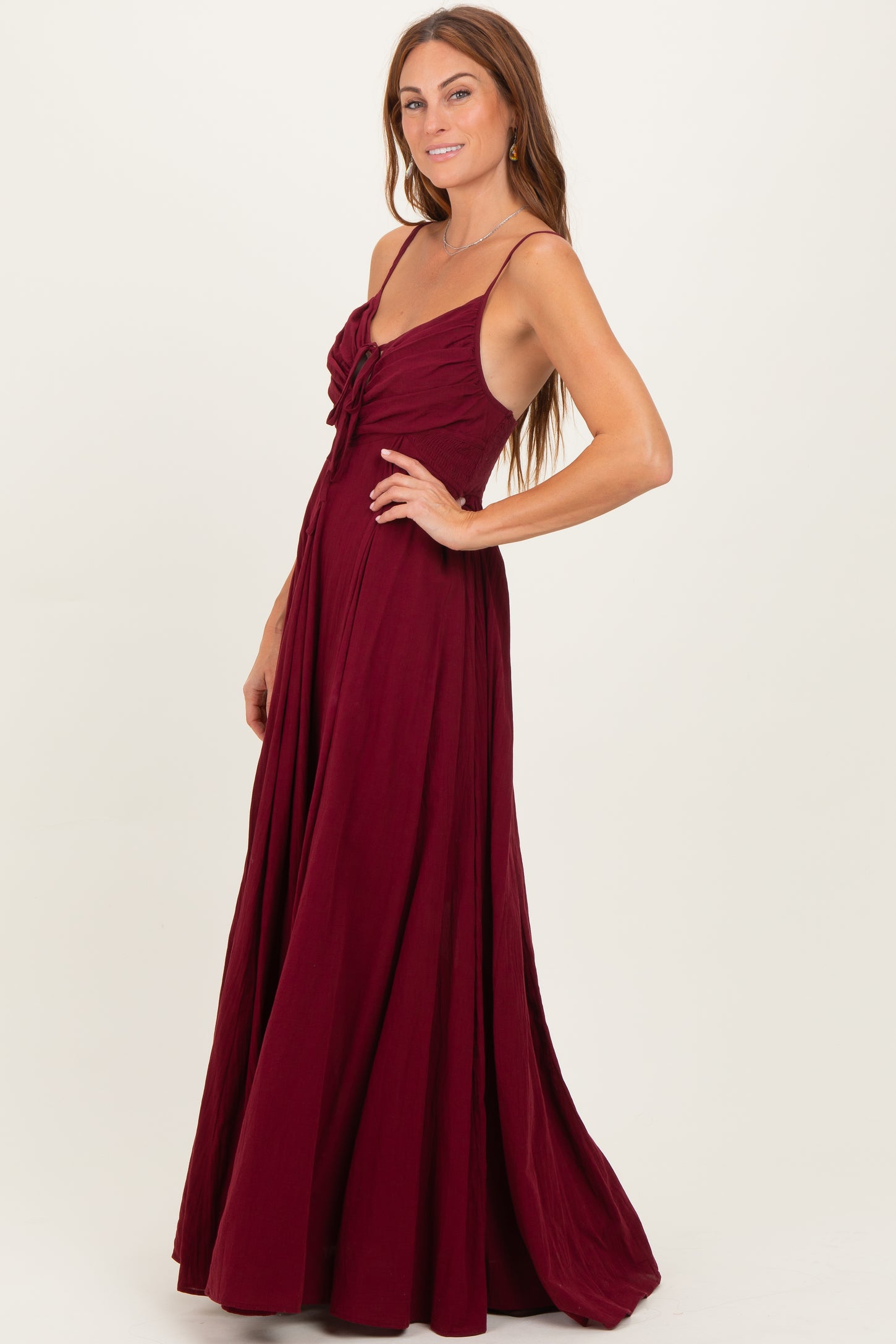 woman wearing a burgundy long maxi dress with a tie detail at the bodice and flowing skirt