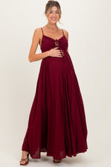 woman wearing a burgundy maternity maxi dress with a tie-front detail and holding her baby bump