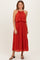 woman wearing a red sleeveless pleated maxi dress with a layered bodice and standing in a relaxed pose