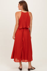 woman wearing a red pleated midi dress with a halter neck and button details on the back