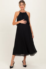 woman wearing a black pleated maternity dress and holding her baby bump