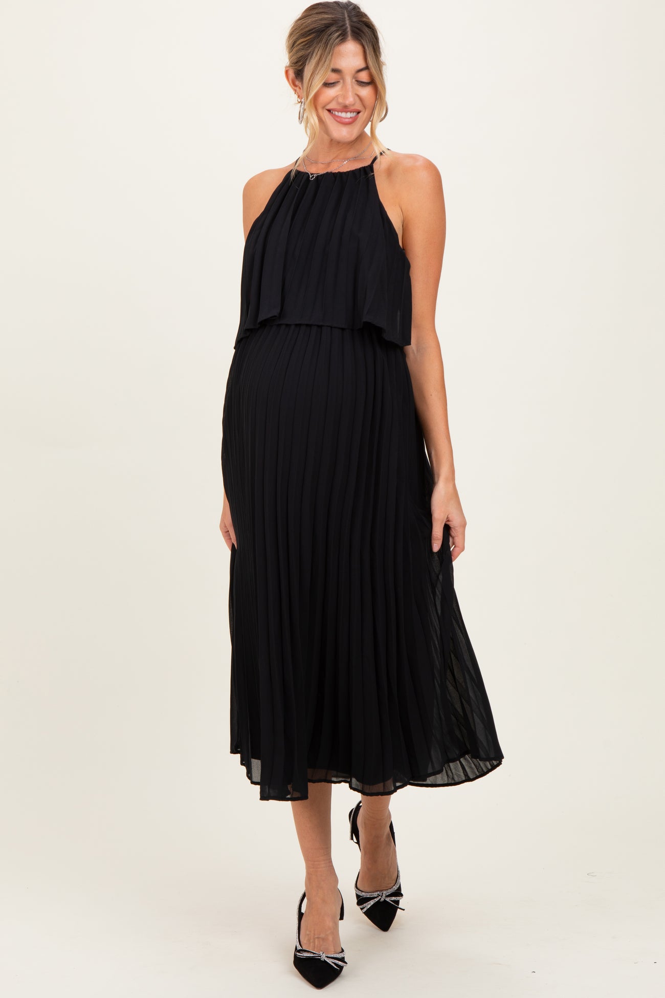 woman wearing a black pleated maternity dress with a halter neck and visible baby bump