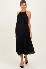 woman wearing a black pleated maternity dress with a halter neck and visible baby bump
