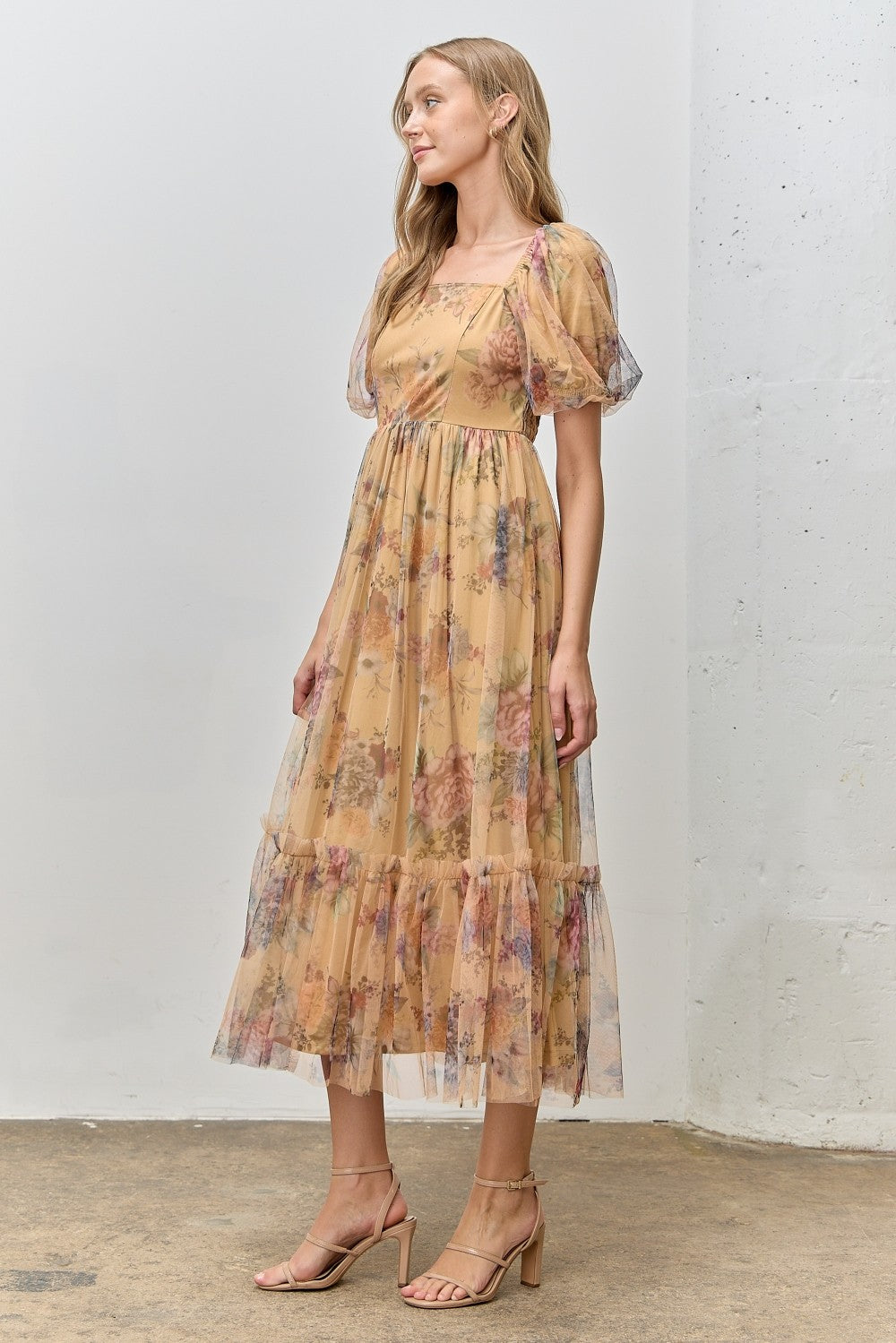 woman wearing a floral print yellow maxi dress with puff sleeves and a tiered skirt, styled with strappy heels