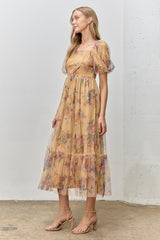 woman wearing a floral print yellow maxi dress with puff sleeves and a tiered skirt, styled with strappy heels