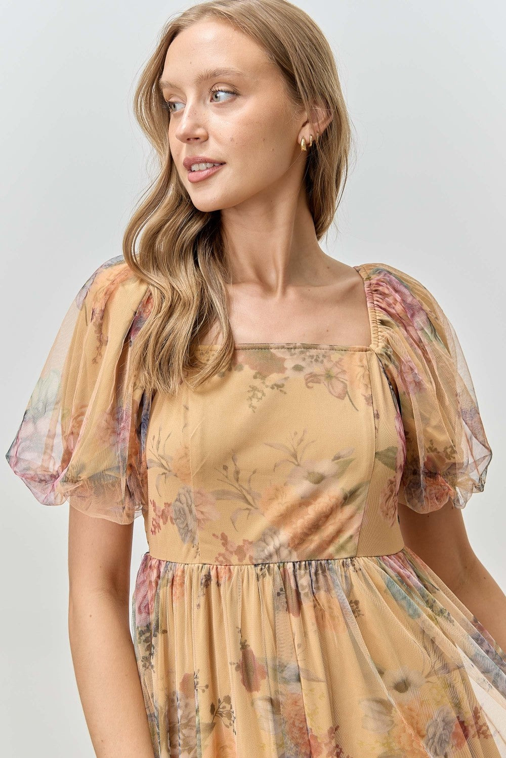 woman wearing a floral yellow dress with puff sleeves and a square neckline