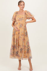 woman wearing a flowy yellow floral maternity dress with puff sleeves and a tiered skirt, holding her baby bump