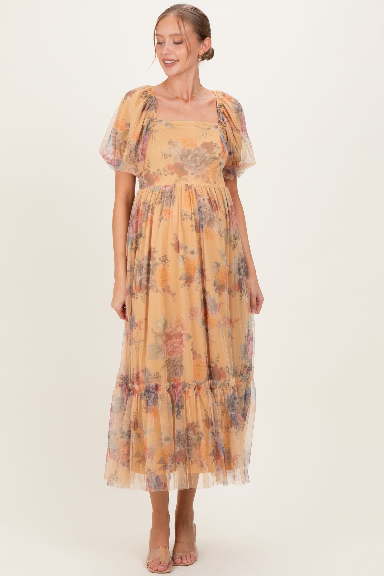 woman wearing a yellow floral maternity dress with puff sleeves and a tiered skirt, showcasing her baby bump