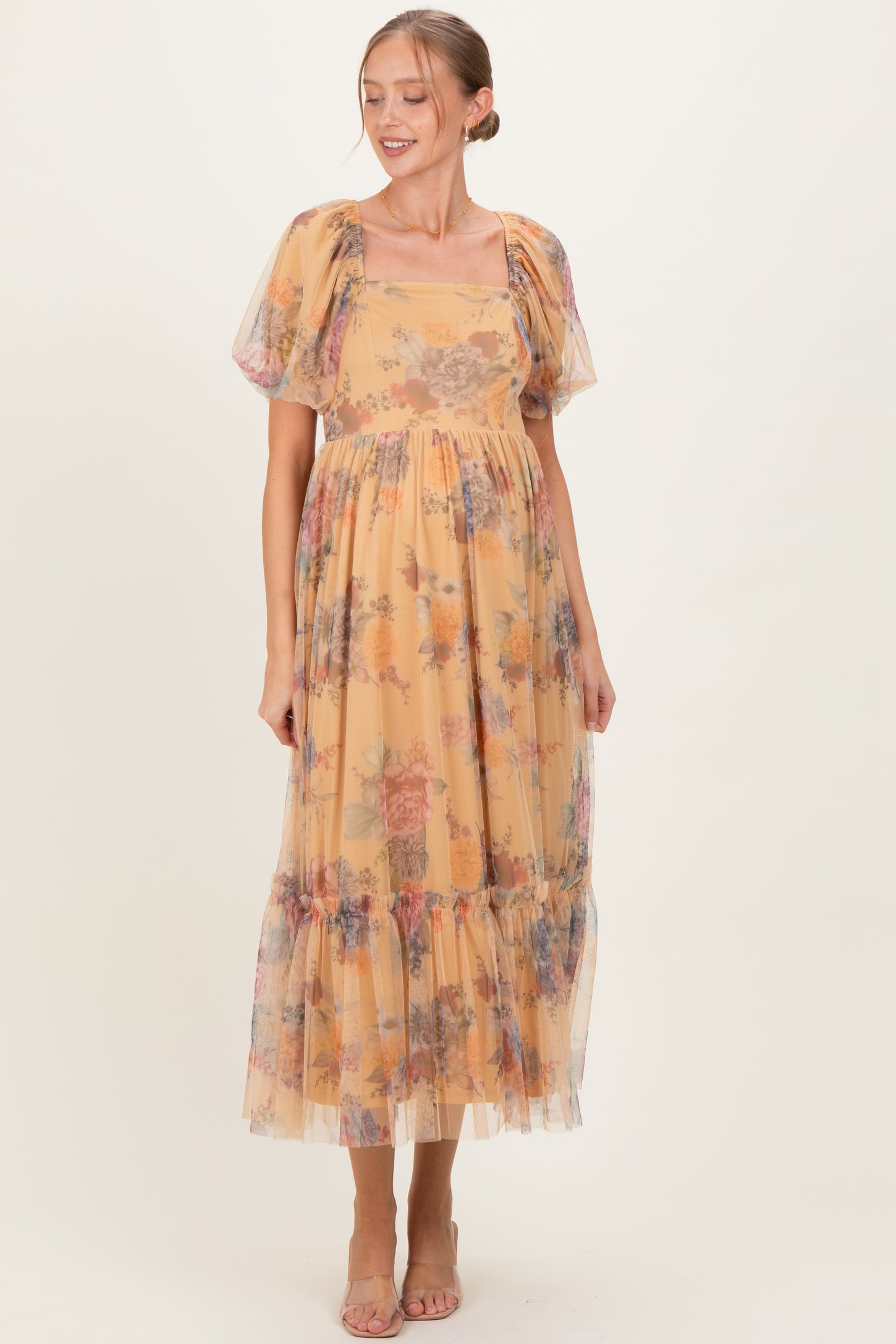 woman wearing a yellow floral maternity dress with puff sleeves and a tiered skirt, showcasing her baby bump