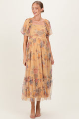 woman wearing a yellow floral maternity dress with puff sleeves and a tiered skirt, showcasing her baby bump
