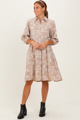 woman wearing a beige floral print shirt dress with three-quarter sleeves and ankle boots