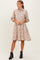 woman wearing a beige floral print shirt dress with three-quarter sleeves and ankle boots