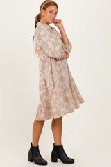 woman wearing a beige floral print long sleeve dress with a ruffled hem and black ankle boots