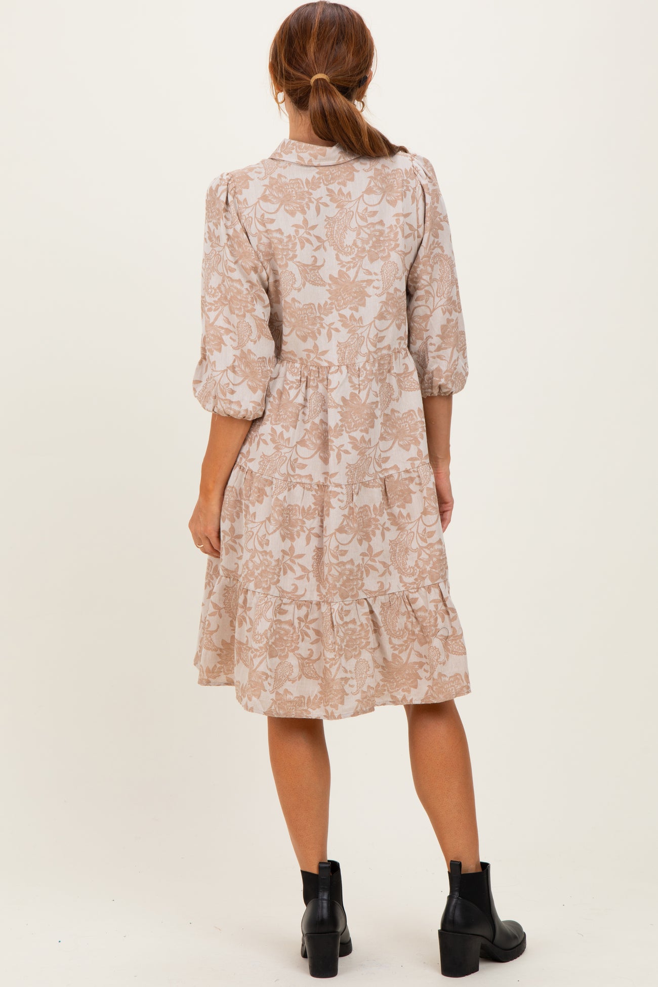 woman wearing a beige floral dress with three-quarter sleeves and tiered hem, shown from the back