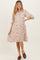 woman wearing a beige floral print maternity dress with a button-down front and three-quarter sleeves