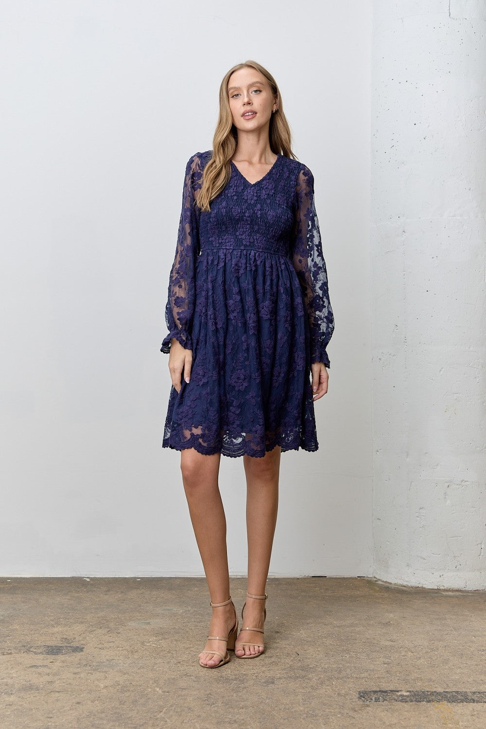 woman wearing a navy blue lace long sleeve dress with a v-neck and a flared skirt