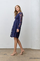 woman wearing a navy blue lace dress with long sleeves and a flowy skirt, styled with nude strappy heels