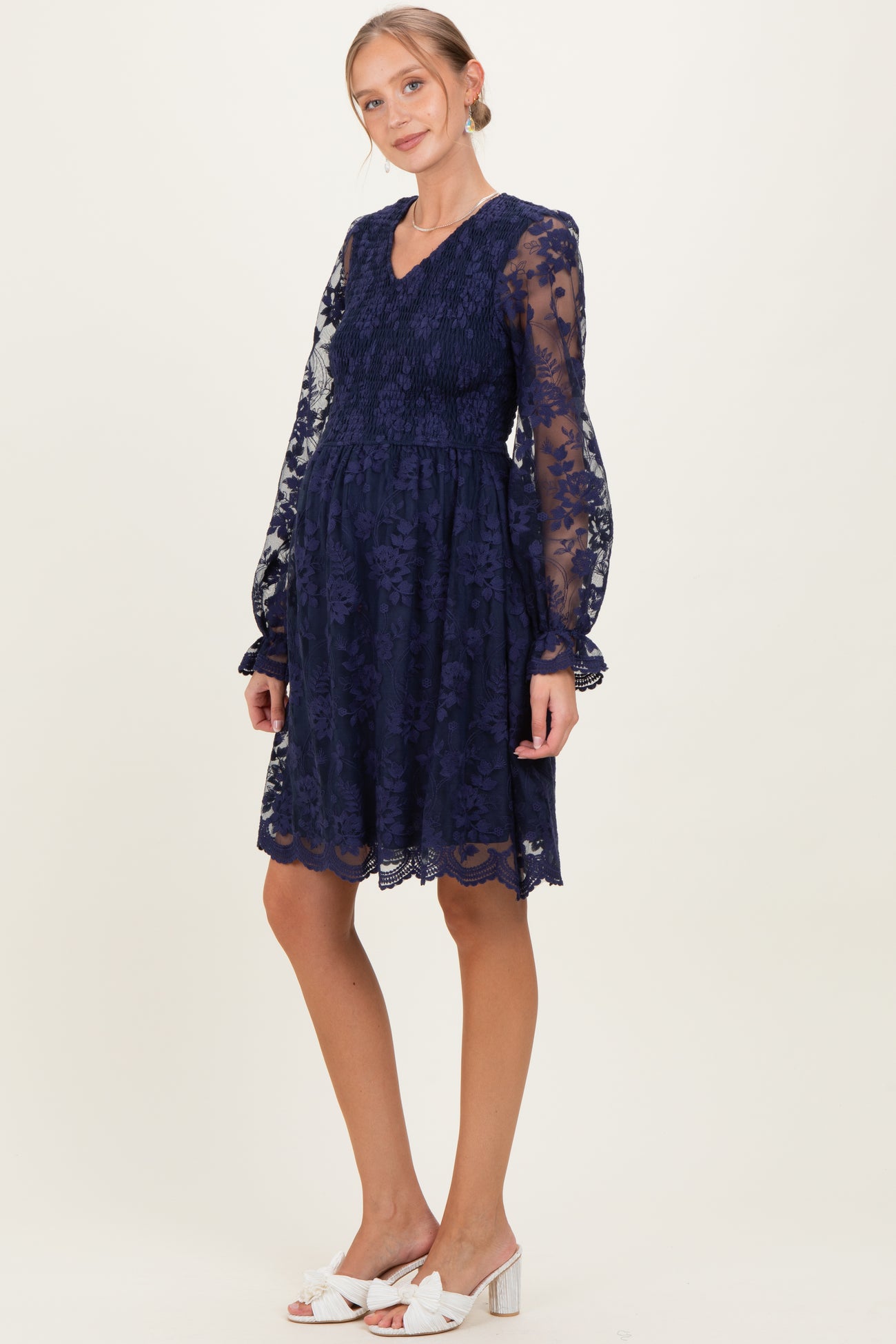 woman wearing a navy blue lace maternity dress with long sleeves and a v-neck, showcasing a baby bump