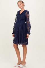 woman wearing a navy blue lace maternity dress with long sleeves and a v-neck, showcasing a baby bump